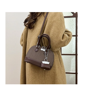 Detail of shell-shaped crossbody bag with herringbone fabric and brown leather handle