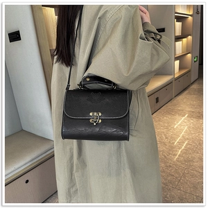 Detail of vintage black crossbody bag with lotus embossing and metal lock closure