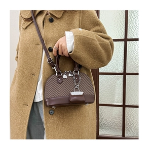 Detail of vintage patchwork shell bag with herringbone fabric and brown leather accent