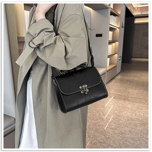 Close-up of black retro square bag featuring embossed lotus pattern and metal clasp
