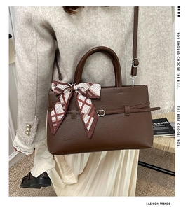Close-up of deep brown lychee texture leather bag with elegant silk scarf handle decoration