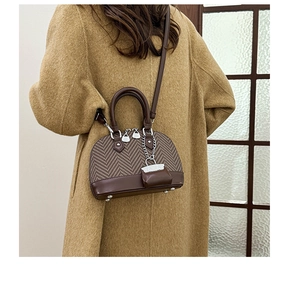 Detail of dark brown shell-shaped crossbody bag featuring textured fabric patchwork