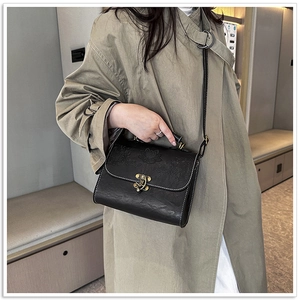Detailed view of black retro handbag with lotus embossing and antique metal hook clasp