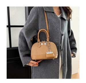 Detail of herringbone fabric and brown leather shell bag worn with a wool coat