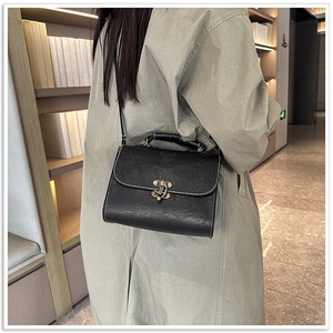 Detail of vintage embossed lotus on black crossbody bag with bronze metal lock