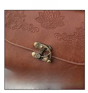 Close-up of vintage bronze buckle and lotus embossed texture on brown leather bag