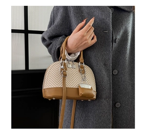 Detail of shell-shaped patchwork handbag featuring woven texture and brown leather accents