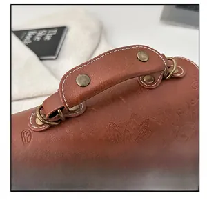 Close-up of vintage brown leather bag with lotus embossing and white contrast stitching