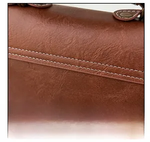 Close-up of retro brown PU leather shoulder bag with detailed white double stitching