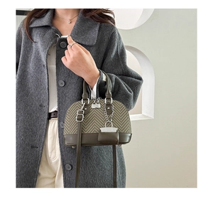 Detail of olive green shell bag with herringbone fabric and metal zipper worn with grey coat