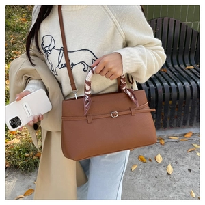 Detailed view of brown lychee grain leather tote bag with decorative silk scarf handle