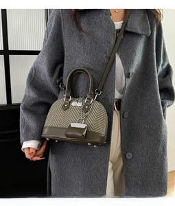 Detailed side view of an olive green patchwork shell bag with woven texture and mini charm