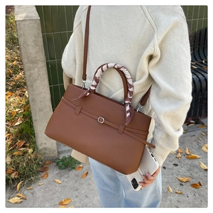 Detail of lychee textured leather tote bag with scarf-wrapped handle on a model