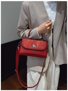 Detail showing red leather and striped velvet textures on a messenger bag with lock