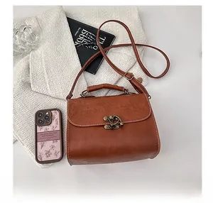 Detail of vintage brown PU leather handbag featuring floral embossing and bronze metal lock