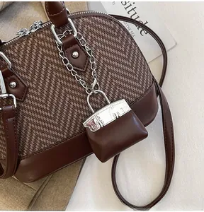 Close-up of brown patchwork shell bag featuring houndstooth texture and leather details