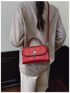 Detailed shot of a red leather crossbody bag featuring silver turn-lock and key charm decoration