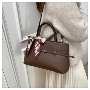 Detail of lychee pattern leather tote bag with elegant silk scarf wrapped on handle