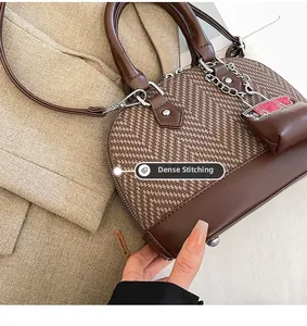 Detail showing fine stitching and leather texture on a vintage shell bag with chain