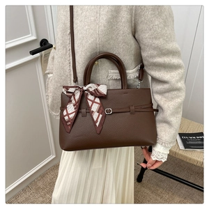 Close-up of luxury brown litchi grain tote bag with geometric silk scarf handle detail