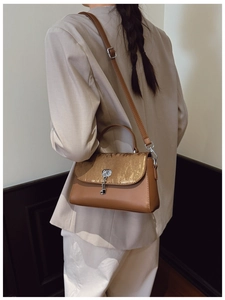 Detail of vintage brown messenger bag with gold pleated flap and silver metal lock pendant