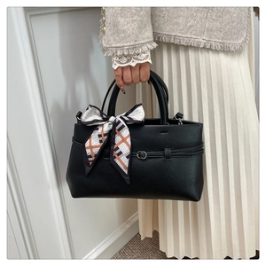 Detailed view of black lychee grain leather tote with a silk scarf handle decoration