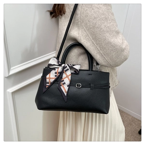 Detail of black litchi texture tote bag featuring a decorative silk scarf and metal buckle