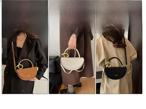 Detail view of stylish saddle bag with unique gold spiral handle in brown, white and black