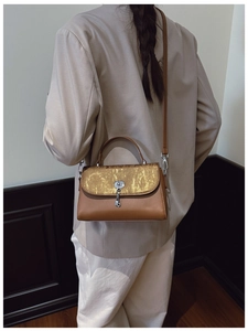 Detail of vintage brown leather messenger bag with shimmering gold flap and metal clasp