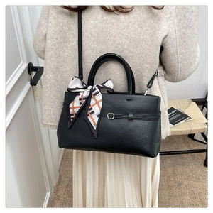 Detail of black litchi pattern tote bag with decorative geometric print silk scarf