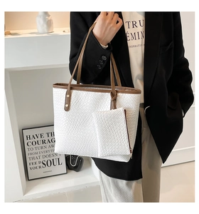 Close-up of white woven leather tote bag set with brown handles and matching pouch