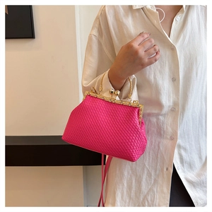 Dettaglio borsa da sera intrecciata rosso rosa con cornice dorata e fermagli di perle