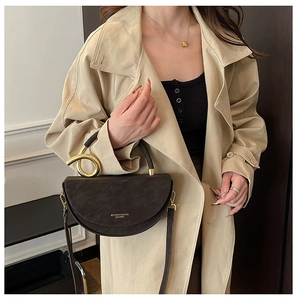 Detail of dark brown crescent bag with gold knot hardware and matte leather texture