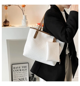 Detail of woven texture tote bag with brown straps and matching small pouch