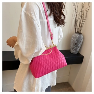 Detail of rose red woven handbag with gold metal frame worn by model on shoulder