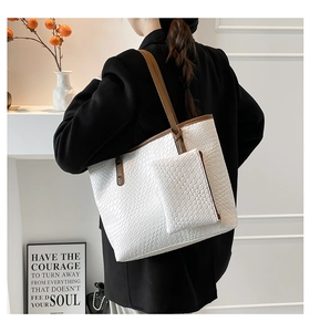 Detail of white woven tote bag with matching small pouch and brown shoulder straps