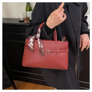 Close-up of red lychee pattern tote bag with decorative silk scarf and metal hardware