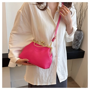 Detailed close-up of rose pink woven leather shell bag with gold clasp held by a model