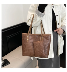 Dettaglio della borsa tote intrecciata marrone con pochette coordinata e rivetti in ottone