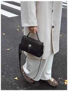 Detail shot of the black messenger bag with grey animal texture flap and silver hardware