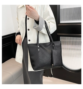 Close-up of black woven texture tote bag and mini pouch on model in white trench coat