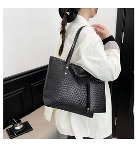 Detail of black woven textured tote bag with coin purse shown on a model for scale