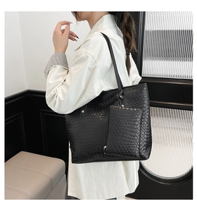 Dettaglio della borsa tote intrecciata nera con pochette abbinata su una modella