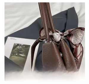 Detail of silver metal hardware and lychee grain leather stitching on tote bag with scarf