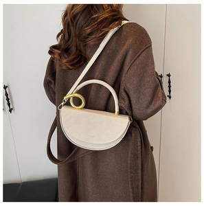 Detail of a beige half-moon leather crossbody bag with gold rings and a long shoulder strap