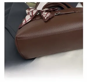 Close-up of brown litchi pattern leather tote with decorative silk scarf and silver hardware