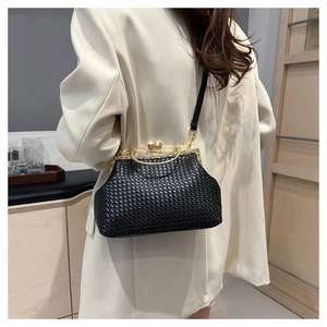 Close-up of black woven texture shell bag with diamond-encrusted gold metal clasp frame