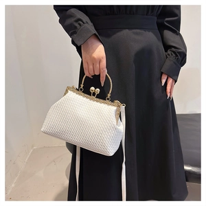 Dettaglio della pochette da sera intrecciata bianca con cornice d'oro e chiusura a perla