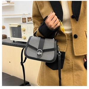 Detail of grey textured crossbody bag with black leather trim and silver round clasp