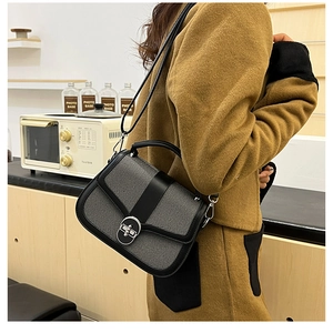 Detail of black leather and grey tweed patchwork handbag with silver oval twist lock clasp